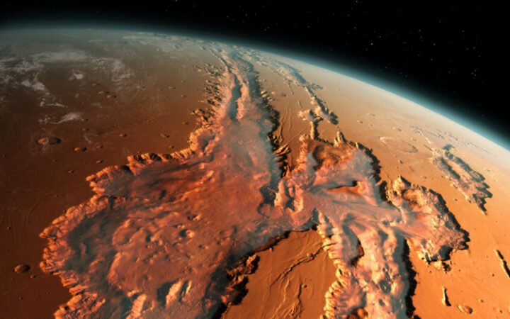رسم توضيحي يقدم مشهدا مائلا لنظام أخاديد وادي مارينير (Valles Marineris) العملاق على كوكب المريخ، يبرز الوادي كشق ضخم يقطع سطح الكوكب الأحمر، ممتدا عبر مسافات شاسعة، وتهيمن درجات اللون البرتقالي، البني المحمر، والترابي على السطح